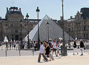 Turista descansa em um banco na praça Carrousel, em frente ao museu do Louvre