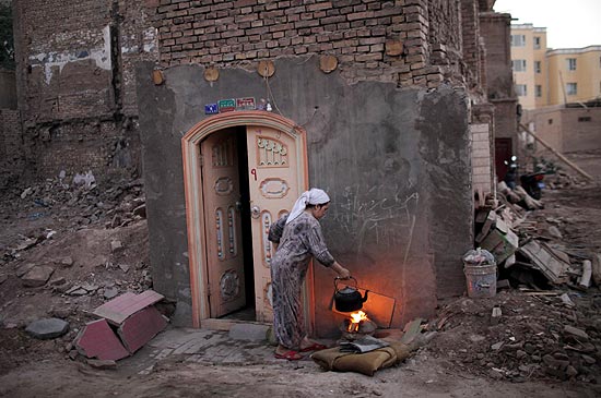Mulher cozinha em sua casa em meio a runas do bairro velho de Kashgar