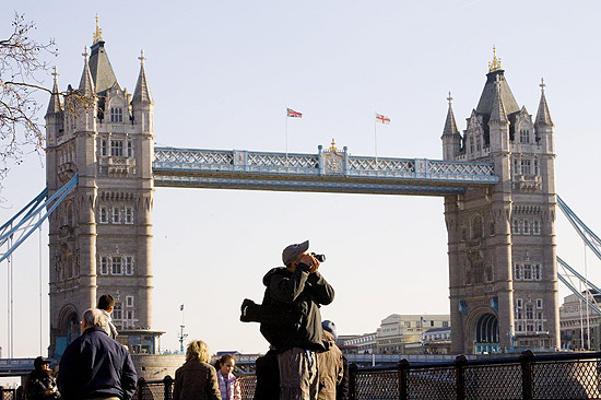 Turista fotografa s margens do Rio Tmisa, com a torre de Londres ao fundo