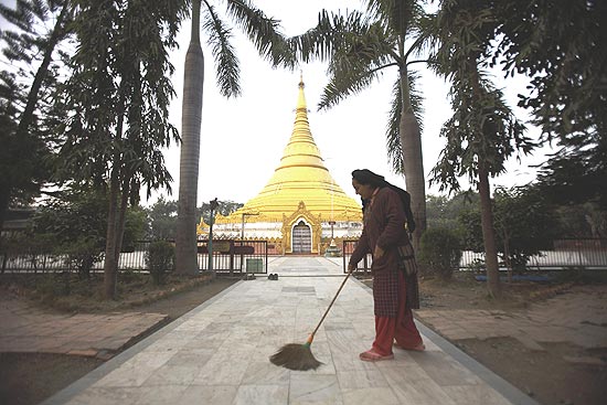 Mulher varre entrada do Templo Dourado, em Lumbini; cidade quer atrair mais turistas