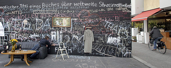 Homem escreve com giz na obra "Muro da Paz", instalada na capital alemã
