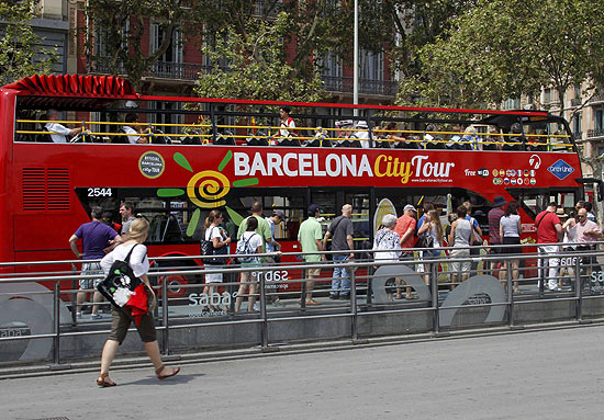 Turistas fazem fila para embarcar em nibus de city tour na cidade de Barcelona, na Espanha