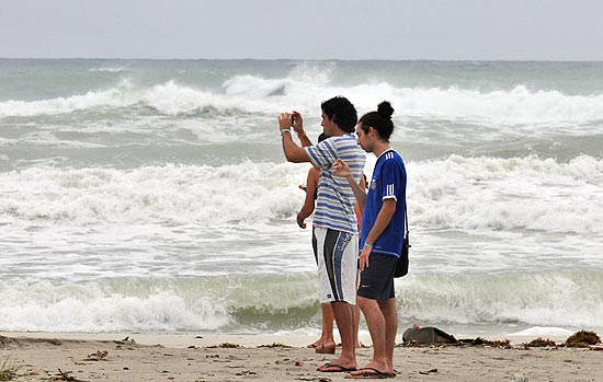 Grupo de turistas tira fotos em praia de Varadero, esperando que a tempestade tropical Isaac se afaste