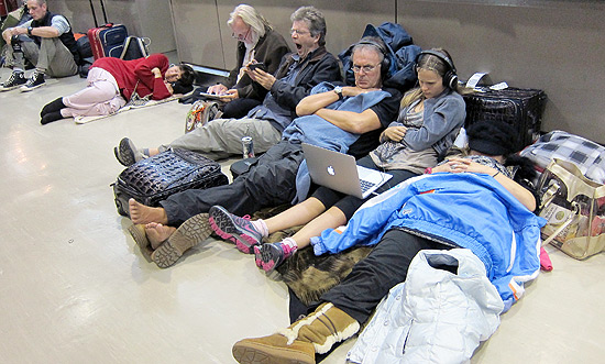 Passageiros descansam no cho do aeroporto internacional de Tquio enquanto aguardam a retomada dos voos