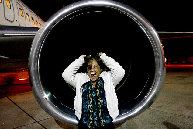 A professora Evaine Cabral posa na frente de turbina de avião, durante visita a aeronave promovida pelo curso Medo de Avião