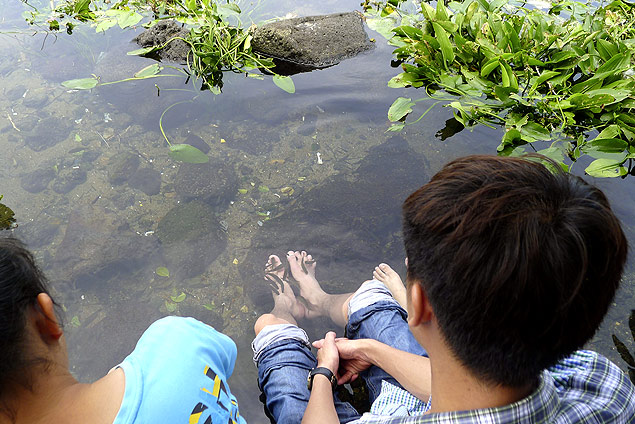 Visitantes da ilha tropical de Hainan desfrutam do lago com temperatura estvel e dos "peixes medicinais"