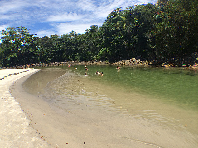 Turistas se refrescam no rio Camburi, no canto esquerdo da praia