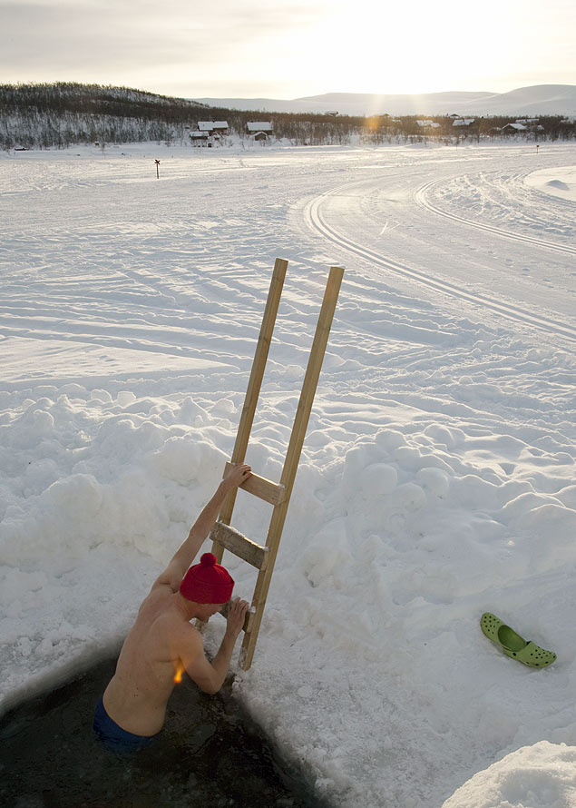 Homem entra em buraco cortado no gelo na Finlndia, a prtica  comum no pas 