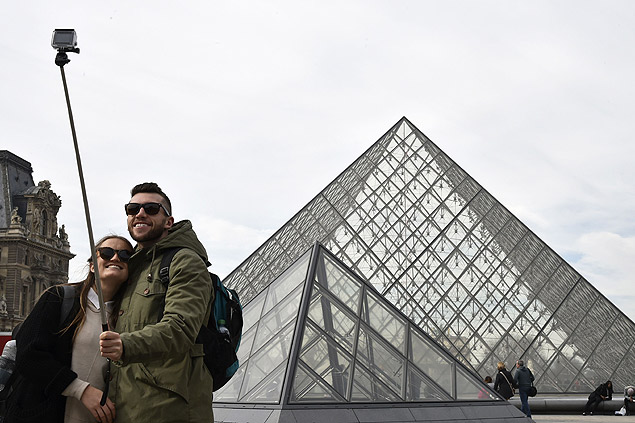 Turistas usam "pau de selfie" para tirar foto em frente a pirmide do Museu do Louvre, em Paris
