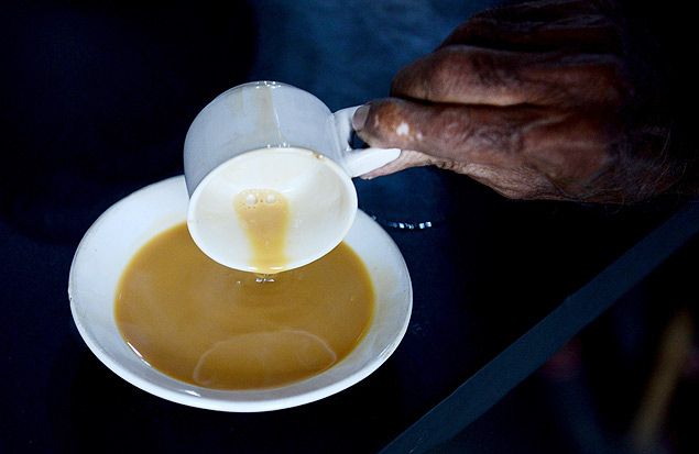 In this photograph taken on August 10, 2015, an Indian customer pours 'Irani chai-tea' into a saucer at The May Rose Cafe in Hyderabad. Irani chai defined the caf culture and it has been a tradition since the 1940s, from Secunderabd to the old city of Hyderabad. Introduced by settlers from Persia (Iran). Persian immigrants came to Mumbai&#146;s port in search of a better life and to trade. From Mumbai they migrated to Pune and then to Hyderabad. Along with them came the concept of Irani chai. Irani chai is mostly served in a white ceramic cup and saucer and often called 90 ml chai after its standard volume, and costs in the range of Indian Rupees 10-12 (USD cents 0.16-0.19). AFP PHOTO/NOAH SEELAM ORG XMIT: NS014