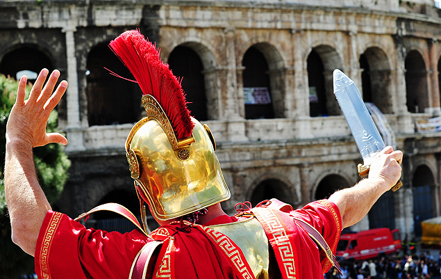 (FILES) - A man dressed as a Roman centurion and who earn his living by posing with tourists gestures in front of the Colosseum during a protest on April 12, 2012 in Rome. Rome Commissioner Francesco Paolo Tronca banned the costumed centurions from posing for photographs with tourists for a fee on November 26, 2015 ahead of the Pope's Jubilee. Rickshaws who offered tourists an alternative to horse-drawn buggies were seized in the interests of 