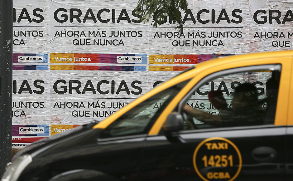 Txi passa em frente a cartazes da campanha eleitoral argentina. em Buenos Aires