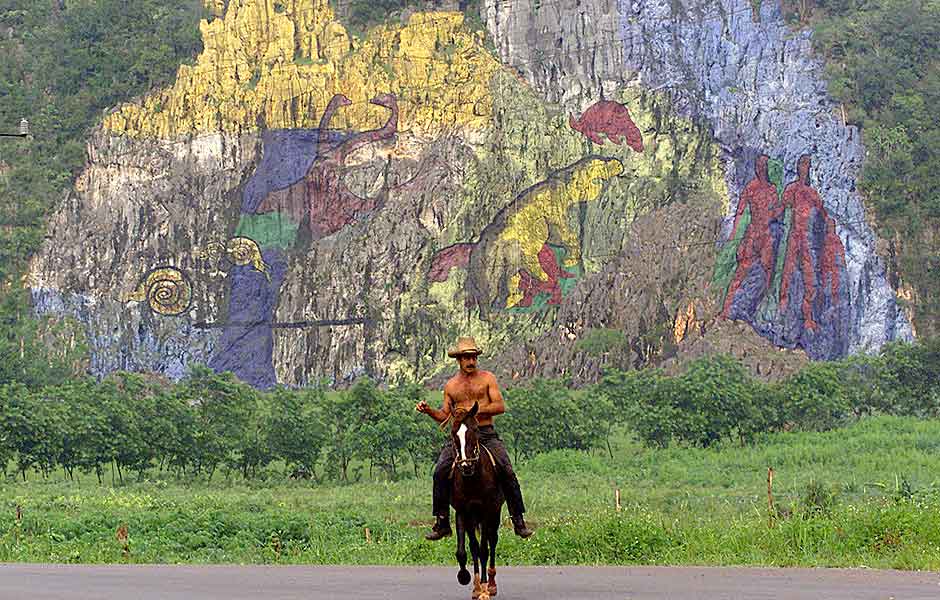 Cubano cavalga em frente a pedra com desenhos em Viñales 