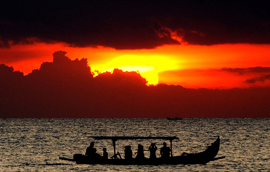 TOPSHOTS Foreign tourists on a traditional boat enjoy the sunset at Kuta beach in Bali on April 26, 2013. According to data from the Central Statistics Agency (BPS) in February 2013, the number of foreign tourists arriving in Indonesia increased 14.5 percent to 678,400 at the beginning of the year. AFP PHOTO / SONNY TUMBELAKA ORG XMIT: SON251