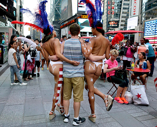 FILE - In this July 28, 2015 file photo, a tourist poses for a photo with two women clad in thongs and body paint in New York's Times Square. Mayor Bill de Blasio has signed a bill that will regulate where and how costumed characters like Spider-Man and Elmo, and the topless women operate. A City Hall ceremony on Thursday April 21, 2016 capped a City Council effort to rein in aggressive panhandlers who have flooded Times Square, with some harassing pedestrians for money. (AP Photo/Julie Jacobson, File) ORG XMIT: NYR104