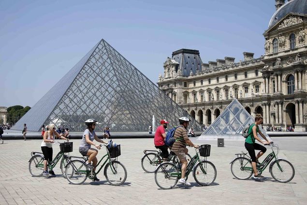 Turistas pedalam prximo  entrada do Louvre, em Paris