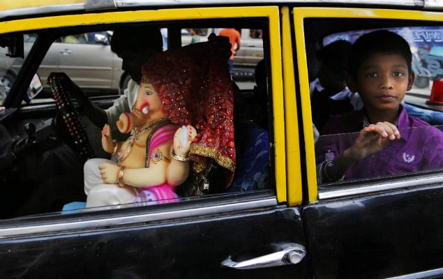 Passageiros carregam esttua do deus Ganesha em txi na cidade de Mumbai