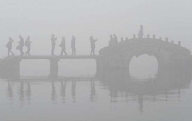 Turistas andam por uma ponte sobre o Lago Oeste de Hangzhou, na China, em meio a uma densa neblina e poluio atmosfrica