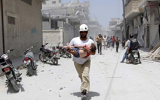 Membro da defesa civil carrega uma menina ferida aps ataques areos na cidade de Maaret al-Numan, provncia de Idlib, na Sria