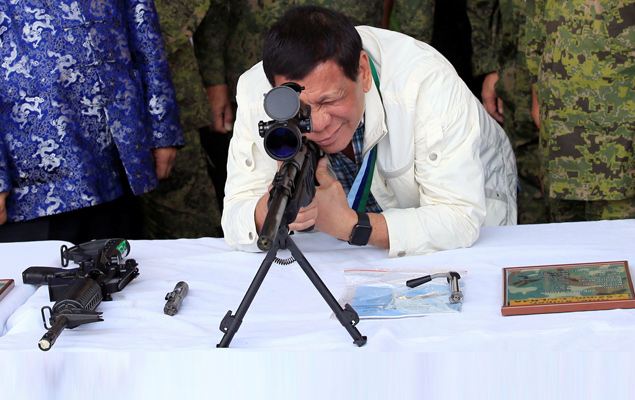 O presidente das Filipinas, Rodrigo Duterte, verifica rifle de franco-atirador em cerimônia de renovação da assistência militar da China, na cidade de Angeles