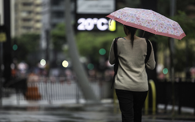 Mulher se protege da chuva na avenida Paulista