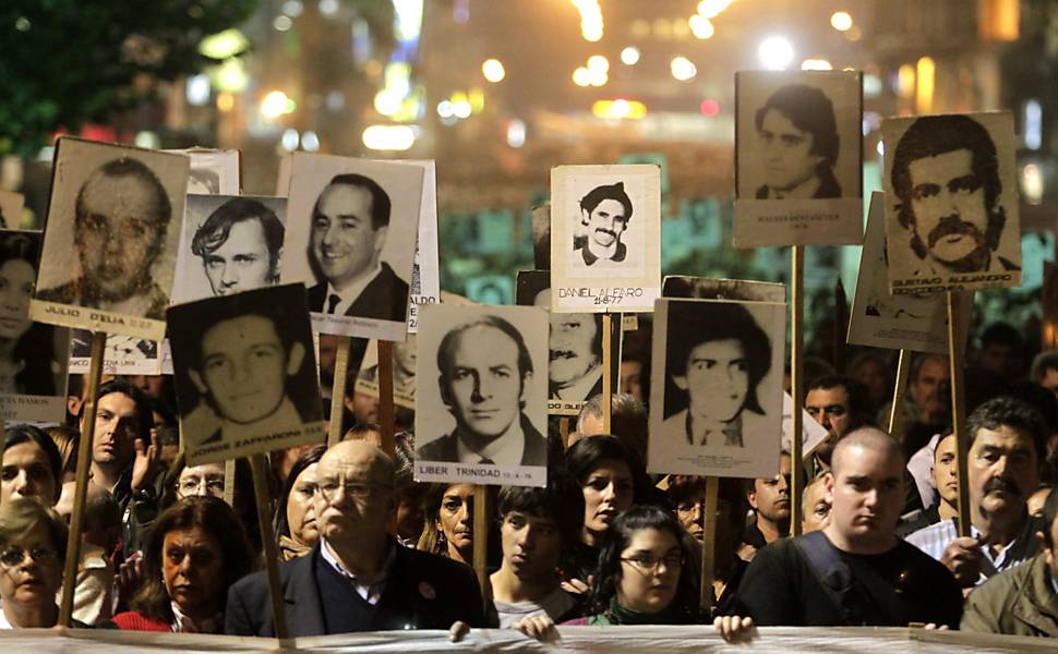 Uruguaios exibem fotos de pessoas desaparecidas durante o regime militar durante passeata em Montevidéu
