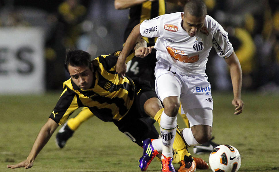 O santista Adriano domina a bola qnaunto Alejandro Martinuccio, Peñarol, tenta marcar Veja mais sobre o jogo