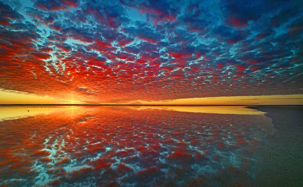 Altos cúmulos no céu são refletidos no Lago Eyre, o maior lago de sal da Austrália, quando ele voltou a encher, em 2010. As secas e cheias do lado estão associadas à chegada dos fenômenos El Niño e La Niña na região Leia Mais