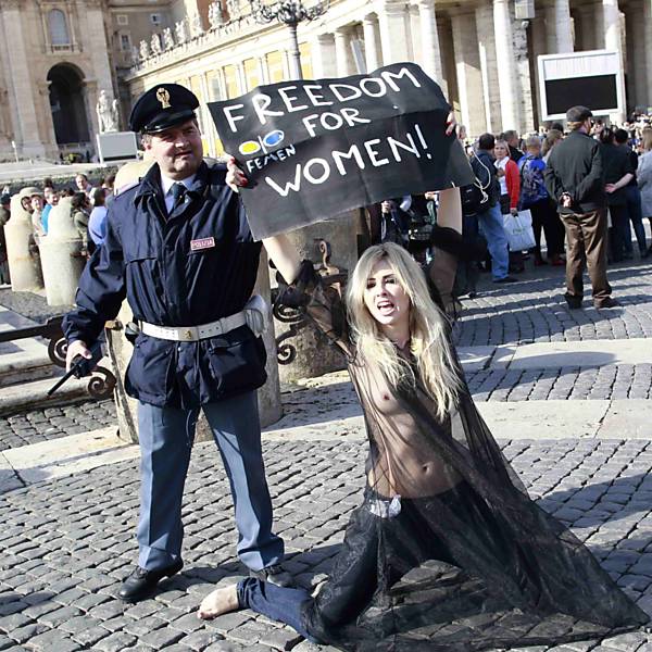 Na Cidade do Vaticano, policial observa ativista do grupo ucraniano Femen, que luta contra a discriminação das mulheres