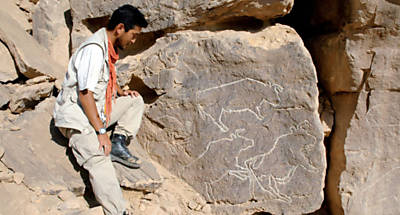 Membro da equipe de escavao ao lado das gravuras, em Qurta, no Egito