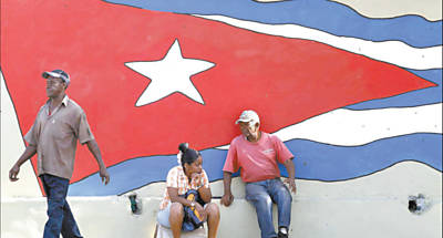 Cubanos em frente  bandeira cubana, pintada em muro; reformas econmicas comearam na ilha dos irmos Castro