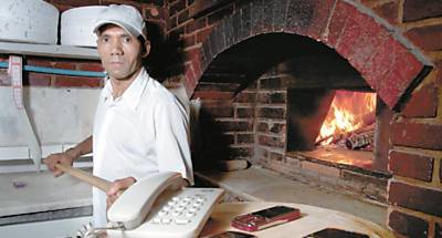 Edisail de Oliveira, dono de pizzaria, mostra telefones para 'delivery