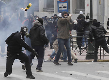 Manifestante atira coquetel molotov contra policiais em Atenas, no primeiro dia da greve geral contra novos cortes