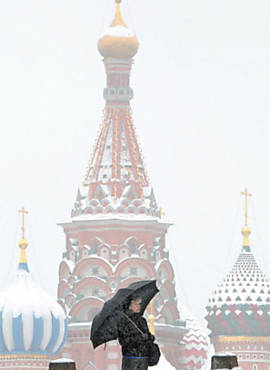 Mulher enfrenta baixas temperaturas na praa Vermelha, em Moscou, com as cpulas da catedral de So Baslio cobertas de branco ao fundo