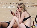 Kirsten Dunst relaxa em praia havaiana enquanto acende um cigarro