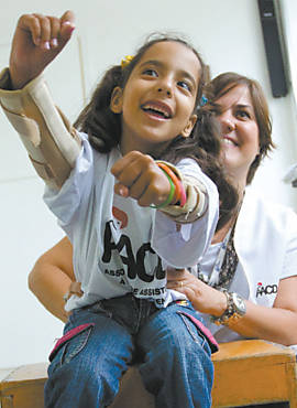 Bianca Felippe, 7, mexe os braos jogando videogame com a fisioterapeuta, na AACD, em SP