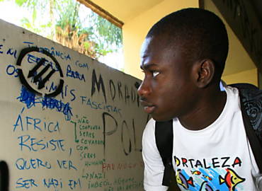 Sumbunhe N'Fanda, de Guiné-Bissau, observa a frase 'Sem cota para os animais da África' parcialmente encoberta