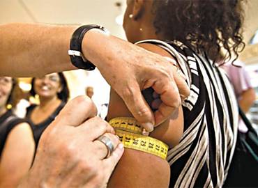 Voluntria mede circunferncia do brao durante campanha contra a hipertenso, em SP