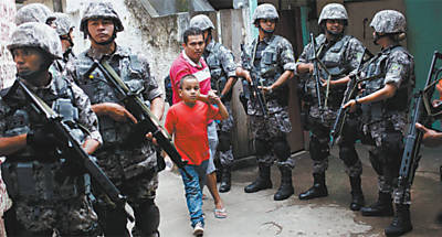 Moradores do morro Santo Amaro caminham no meio de policiais armados