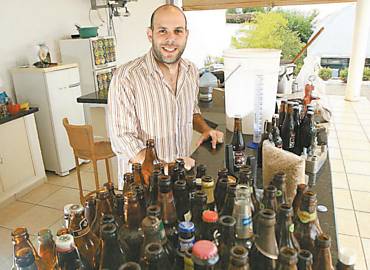 Renato Vergoni, com garrafas e equipamentos usados na fabricao de cerveja em casa
