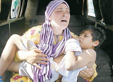 Mulher sria carrega o filho, que foi atingido na mo por um disparo, ao cruzar um rio na fronteira da Sria como Lbano