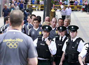 Policiais escoltam a tocha olmpica de Londres-2012 no desfile em Londonderry, na Irlanda da Norte, aps terem de alterar em 100 jardas (cerca de 91 metros) o percurso do evento para evitar o encontro com manifestantes que protestavam contra as foras de segurana da cidade