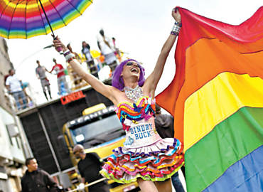 Participante do desfile ergue bandeira com arco-ris durante a Parada Gay na Paulista