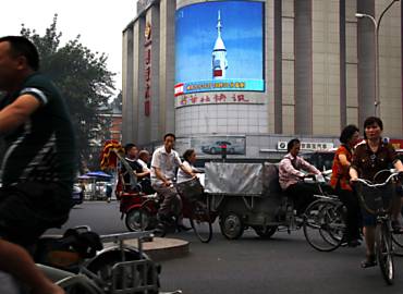 Chineses passam diante de cartaz com imagens do recente o lanamento espacial feito pelo pas, no centro de Pequim