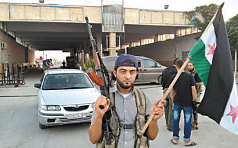 Rebelde srio na fronteira com a Turquia, em Bab Al Salam; ao fundo, a moldura vazia onde ficava um retrato de Assad
