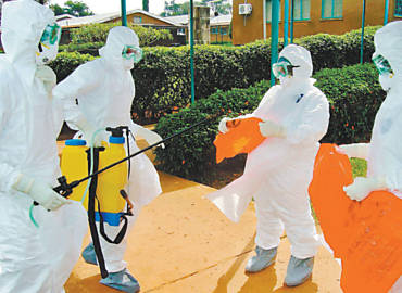 Funcionários da Organização Mundial da Saúde se protegem para entrar em hospital em Uganda, em meio a surto