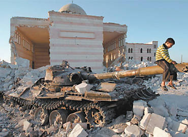 Criana brinca em tanque do Exrcito srio, destrudo e parcialmente coberto pelos destroos de uma mesquita em Aleppo