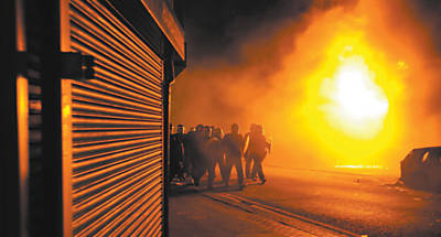 Tropa de choque passa por prdios incendiados em Croydon, na zona sul de Londres, durante as revoltas de agosto de 2011; um ano depois, temor de reedio dos conflitos persiste