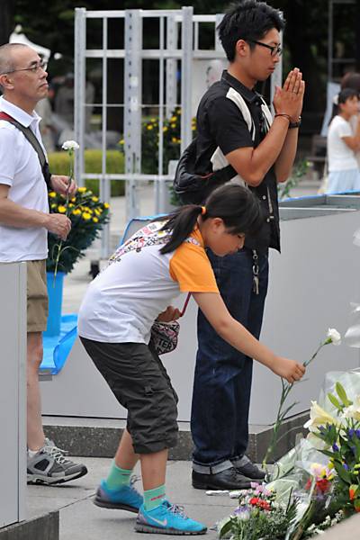 Pessoas rezam e deixam flores no mausoléu em homenagem as vítimas da bomba atômica, em Hiroshima (Japão)