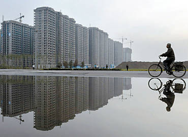 Homem anda de bicicleta perto de complexo residencial na cidade de Taiyuan, na China